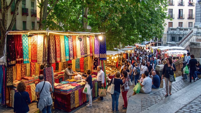 Puestos de telas y gente paseando por el mercado de El Rastro